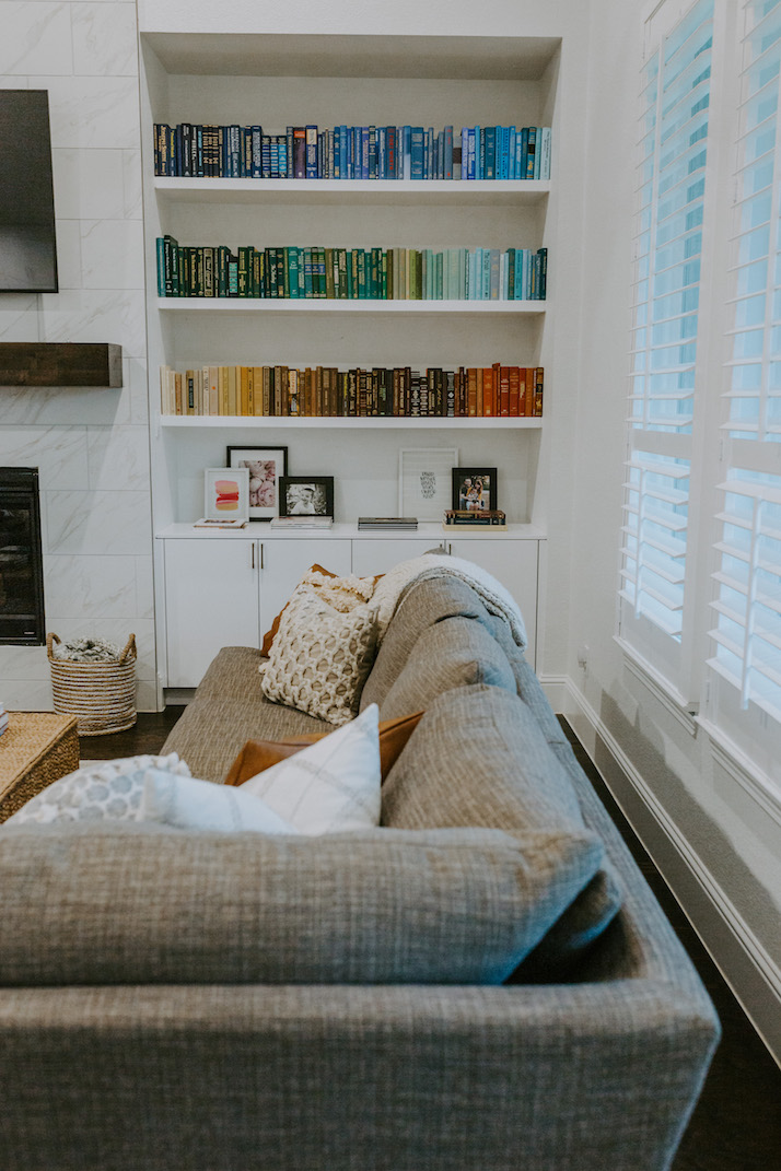 rainbow bookshelf and gray couch living room