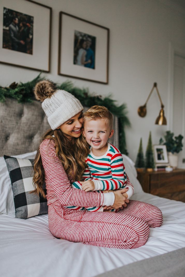mom and son in striped pajamas on gray tufted bed