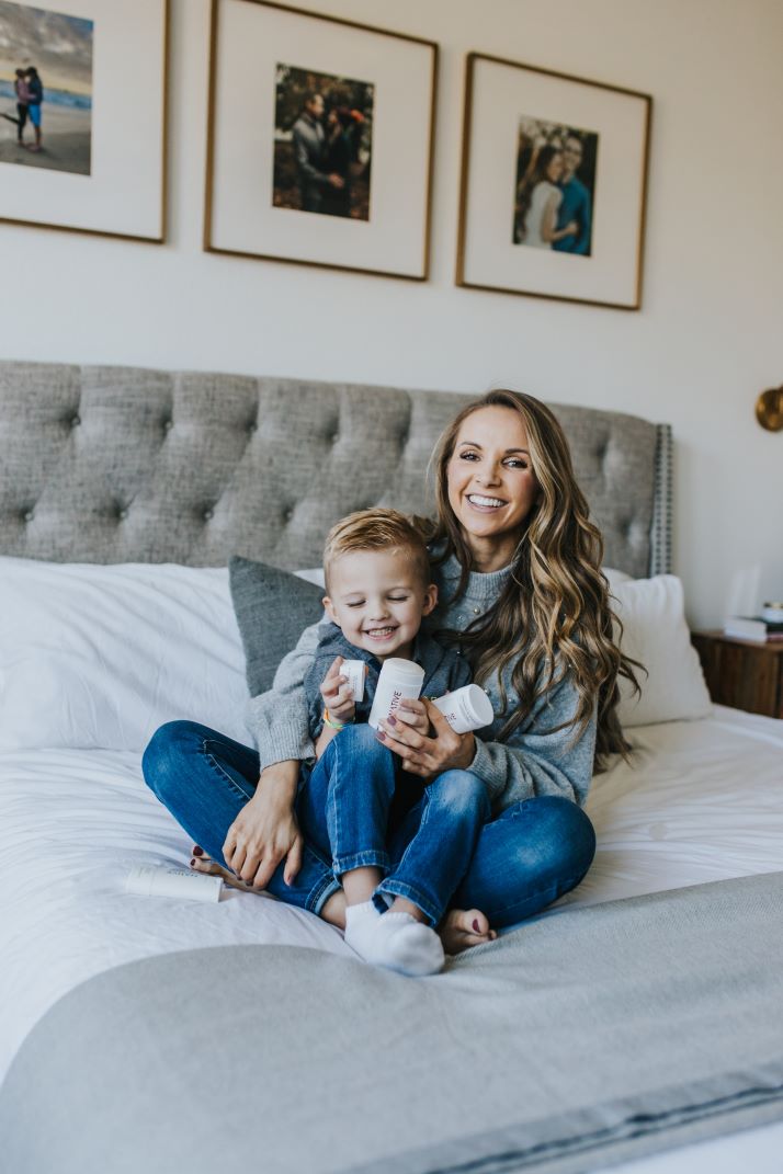 mom and son on bed with gray tufted headboard